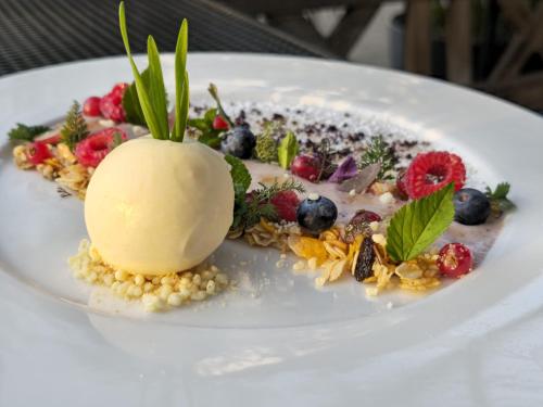 a dessert on a white plate with berries and ice cream at Weinhotel Restaurant Klostermühle in Ockfen