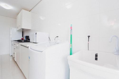 eine weiße Küche mit einer Badewanne und einem Waschbecken in der Unterkunft Apartamento Aconchegante Maia 404 in Caxias do Sul