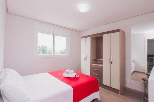 a bedroom with a white bed with a red blanket at Apartamento Aconchegante Maia 404 in Caxias do Sul
