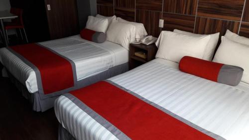Habitación de hotel con 2 camas con sábanas rojas y blancas en Hotel Sunset en Chignahuapan