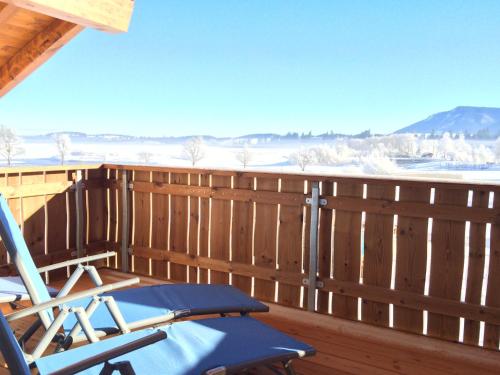 a deck with a rocking chair on a wooden fence at Alpenglück de Luxe Ferienwohnung am Forggensee in Schwangau