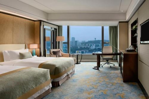 廈門市にあるケンピンスキ ホテル シアメンのベッド2台とデスクが備わるホテルルームです。