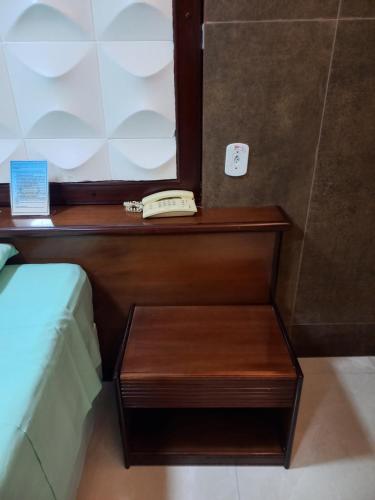 a telephone on a wooden table next to a bed at Barreto Apart-hotel Kubit in Brasilia