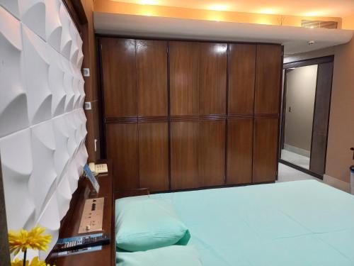 a bedroom with a bed and wooden cabinets at Barreto Apart-hotel Kubit in Brasilia