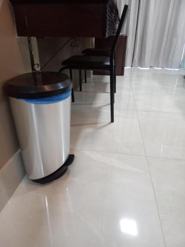 a trash can sitting on a white floor with a chair at Barreto Apart-hotel Kubit in Brasilia