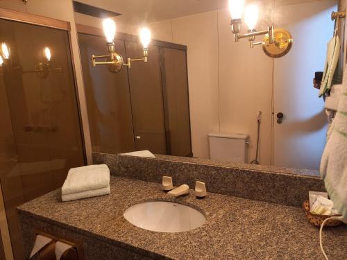 a bathroom with a sink and a large mirror at Barreto Apart-hotel Kubit in Brasilia