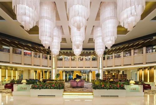 un vestíbulo con lámparas de araña y flores en un edificio en Kempinski Hotel Dalian en Dalian