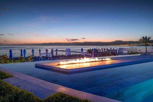 una piscina con una hoguera con el océano en el fondo en Kempinski Hotel Aqaba en Áqaba