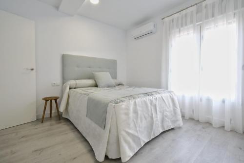 a white bedroom with a bed and a window at Los Miradores del Arrabal in Toledo
