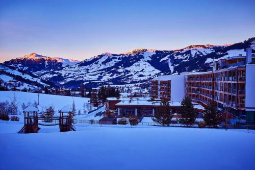 una ciudad cubierta de nieve con montañas en el fondo en Kempinski Hotel Das Tirol en Jochberg