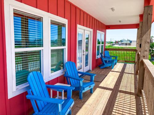 una fila de sillas azules en el porche de una casa roja en Red Fish, Blue Fish, en Aransas Pass
