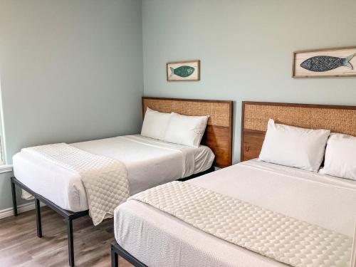 2 camas en una habitación pequeña con sábanas blancas en Red Fish, Blue Fish, en Aransas Pass