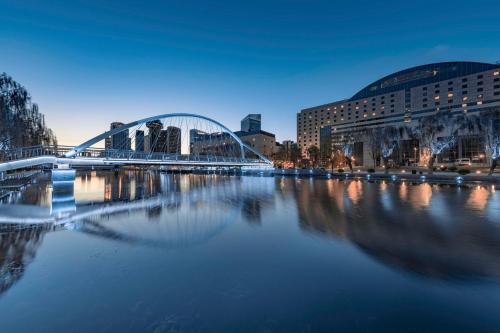 eine Brücke über einen Fluss in einer Stadt nachts in der Unterkunft Kempinski Hotel Beijing Yansha Center in Peking