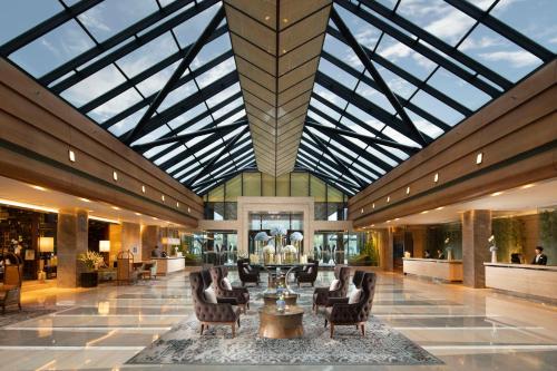 a lobby with a glass ceiling with chairs and a table at Kempinski Hotel Beijing Yansha Center in Beijing