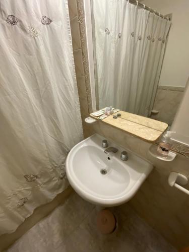 y baño con lavabo blanco y ducha. en Cerquita de Shopping: depto amoblado urbano en Neuquén