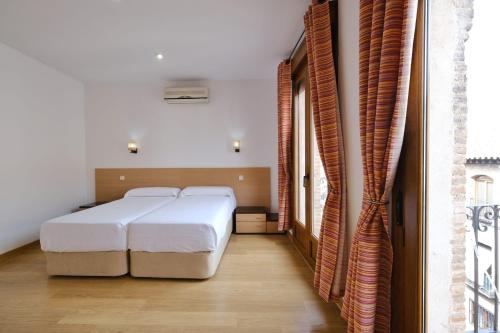 a bedroom with two white beds and a window at Los Miradores del Arrabal in Toledo