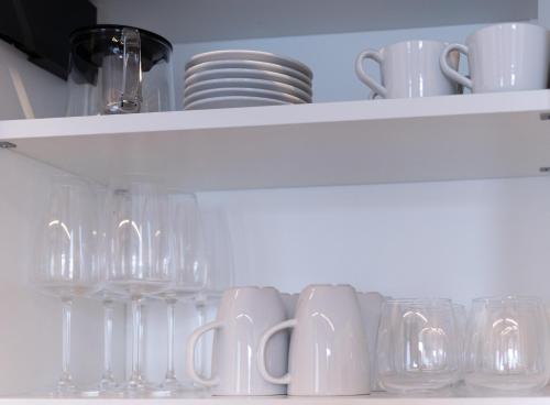 a white shelf with glasses and plates and cups at Belvedere 237 Lakeview Apartment Leo Bakst in Ghiffa