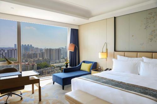 a bedroom with a bed and a desk and a window at Kempinski Hotel Fuzhou in Fuzhou