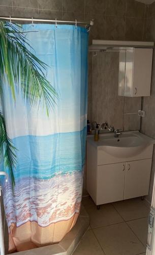 a bathroom with a shower curtain of the beach at Apartmani ARIANA in Dobra Voda