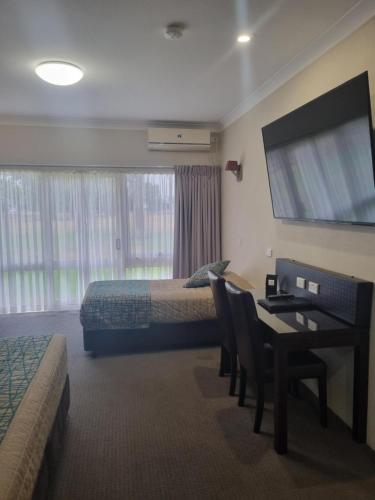 a hotel room with a bedroom with a desk and a bed at Australian Homestead Motor Lodge in Wagga Wagga
