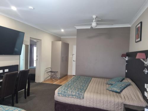 a bedroom with a bed and a desk and a tv at Australian Homestead Motor Lodge in Wagga Wagga