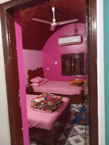 2 camas en una habitación con paredes rosas en Noupian mother, en Asuán