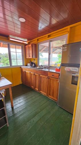 a kitchen with wooden cabinets and a stainless steel refrigerator at Bastimentos Hill Guest House in Bocas del Toro