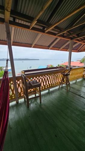 a porch with a bench and a view of the ocean at Bastimentos Hill Guest House in Bocas del Toro
