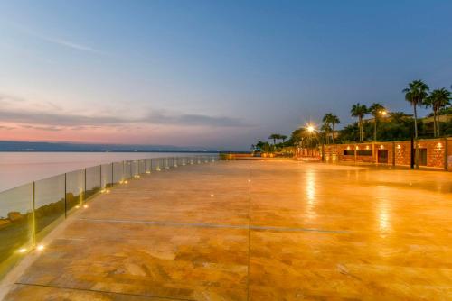 ein Pier in der Nacht mit Palmen und Wasser in der Unterkunft Kempinski Hotel Ishtar Dead Sea in Sowayma