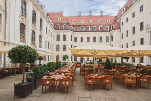 ein Restaurant im Freien mit Tischen, Stühlen und Sonnenschirmen in der Unterkunft Hotel Taschenbergpalais Kempinski in Dresden