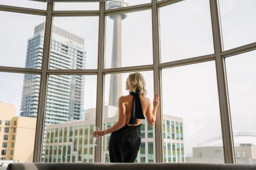 Une femme qui regarde par une fenêtre dans une ville dans l'établissement SoHo Hotel Toronto, à Toronto