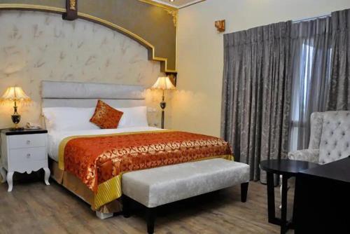 a bedroom with a large bed and a chair at Sandralia Hotel in Abuja