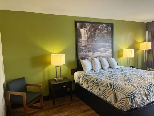 Habitación de hotel con cama y silla en Motel 6 Forsyth, GA Tift College, en Forsyth