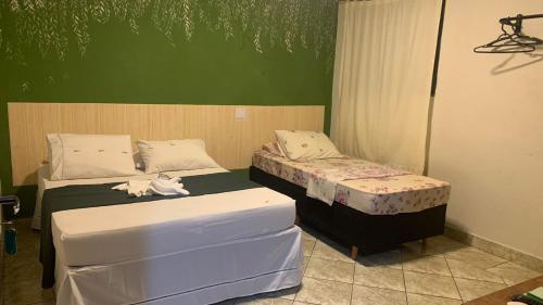 2 camas individuales en una habitación con paredes verdes en BALSAMO HOTEL, en Marília