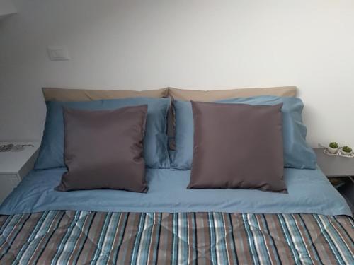 a bed with blue sheets and two brown pillows at casa Gorla in Milan