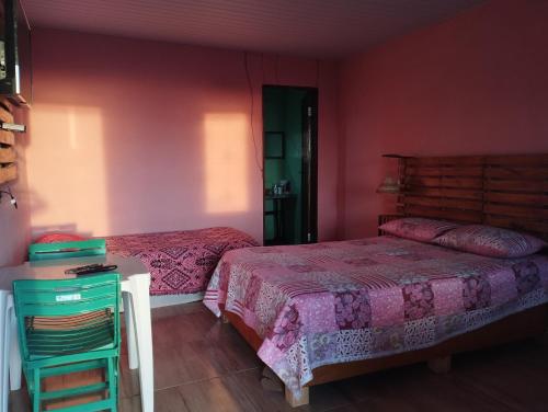 a bedroom with two beds with pink walls and a table at Colina dos Ventos in Mulungu