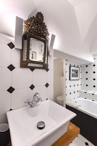 une salle de bain avec un lavabo, un miroir et une baignoire dans l'établissement Spacieux appartement Paris 17ème - Batignolles, à Paris