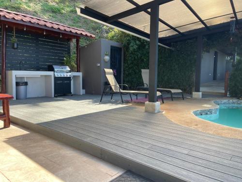 a wooden deck next to a swimming pool with a grill at Villa Del Mar 2 Spectacular ocean view! in Dominical