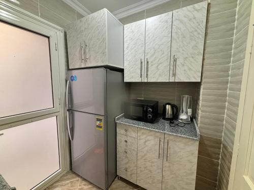 a small kitchen with white cabinets and a refrigerator at Luxury Inn: 2BR Prime location in Madinaty B12 in Madinaty