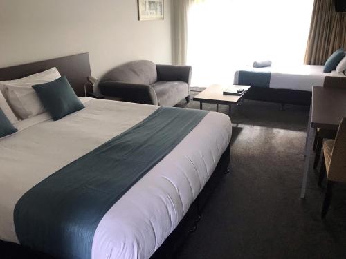 a hotel room with a bed and a living room at Airport Delta Motel in Christchurch