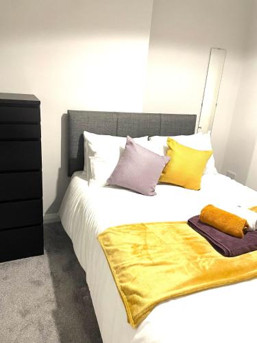 ein Schlafzimmer mit einem großen Bett mit gelben und violetten Kissen in der Unterkunft Ekaya Cozy Home in Belfast