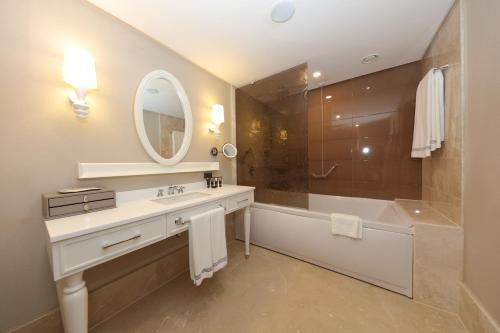 a bathroom with a sink and a tub and a mirror at Sueno Hotels Deluxe Belek in Belek