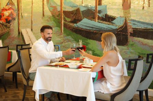a man and woman sitting at a table with wine glasses at Sueno Hotels Deluxe Belek in Belek