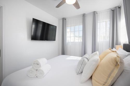 a white bedroom with a large white bed and a flat screen tv at 3 Bedroom House - Fire Pit Table BBQ - 10 Guests in La Mesa