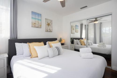 Habitación blanca con 2 camas y espejo. en 3 Bedroom House - Fire Pit Table BBQ - 10 Guests, en La Mesa