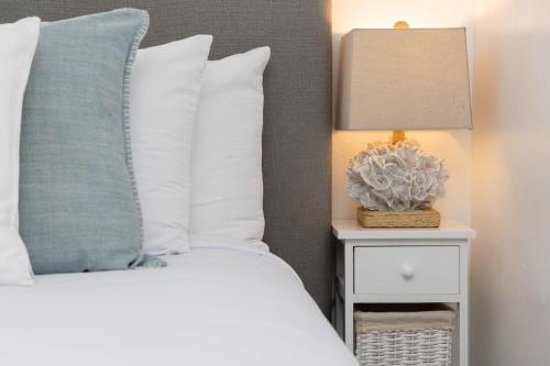 a bed with white pillows and a lamp on a night stand at 3 Bedroom House - Fire Pit Table BBQ - 10 Guests in La Mesa