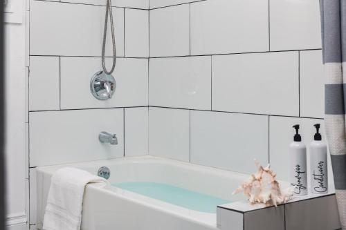 a bath tub in a white bathroom with white tiles at 3 Bedroom House - Fire Pit Table BBQ - 10 Guests in La Mesa