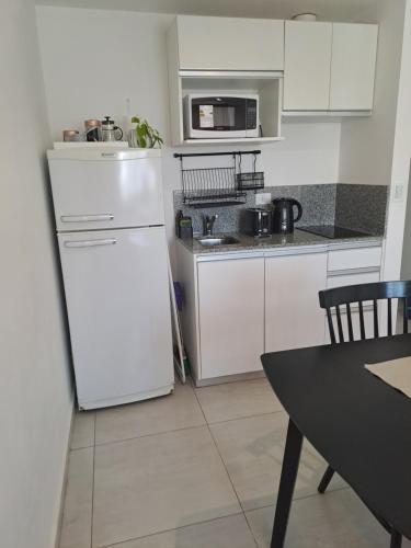 een keuken met een witte koelkast en een tafel bij Cómodo monoambiente en Salta 246 in Neuquén