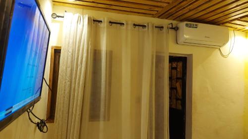 a bathroom with a shower curtain and a television at ETOUDI in Douala