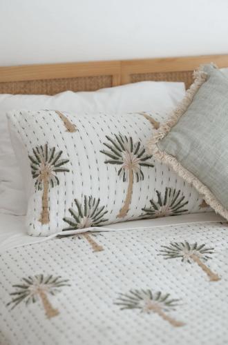 a bed with two pillows with palm trees on it at The Villa's Mooloolaba in Mooloolaba
